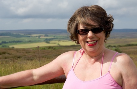 Mature BBW Speedy Bee strips naked in a field while visiting a tourist site