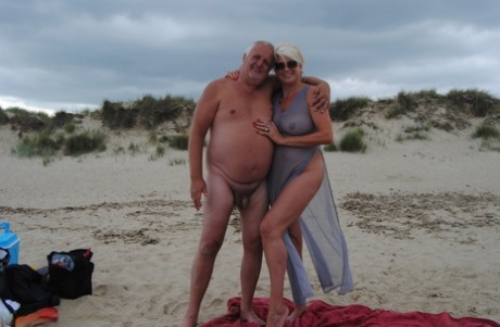 Mature blonde Dimonty eats a frozen treat after posing nude on a beach 56344943