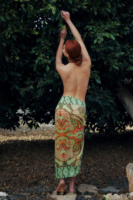 Young redhead Valery Leche removes a sari to pose naked in a garden setting 10037440