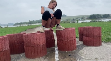 Blonde girl Juliia takes a pee atop cylinder shaped devices that block a road 89187865