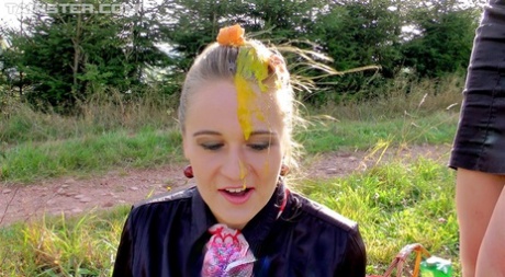 Fully clothed women cover each other in food products while picnicking 97528909